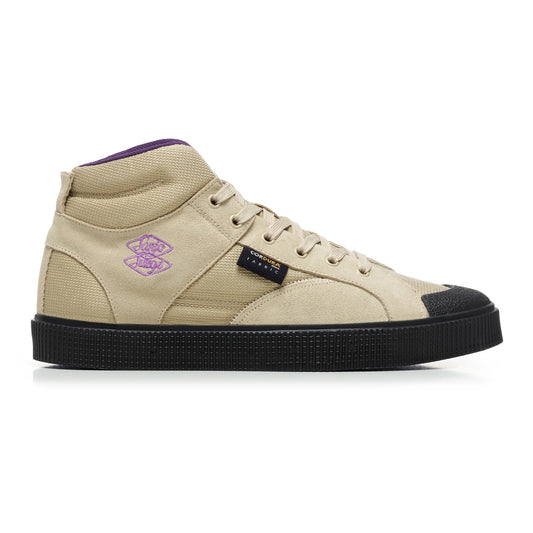 A side view of a Sanjo SK EVO x Surge high-top sneaker, a limited-edition collaboration with Surge magazine. Features a taupe suede and Cordura nylon upper, purple embroidered logo details, a black rubber toe cap, and a textured black outsole for skate durability. Includes a Cordura tag highlighting the material's strength and water resistance.
