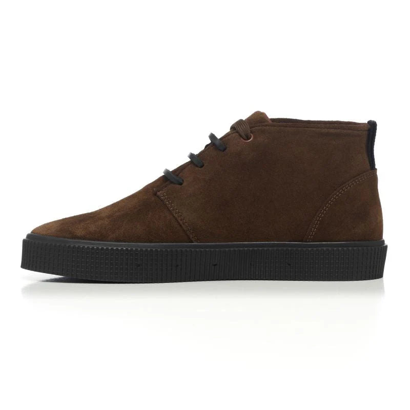 A side view of a Sanjo mid-top suede desert boot in chocolate brown with black laces and a durable black rubber sole, styled with a sleek and versatile design.