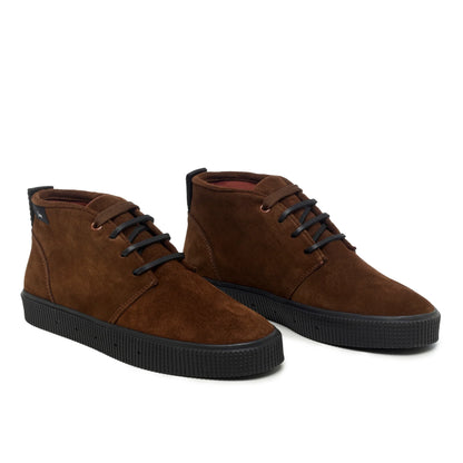 A pair of Sanjo mid-top suede desert boots in chocolate brown with black laces and a durable black rubber sole, styled with a sleek and versatile design.
