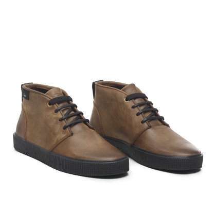 A pair of Sanjo mid-top leather desert boots in brown with black laces and a durable black rubber sole, styled with a sleek and versatile design.